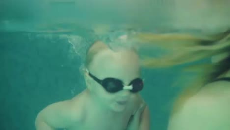 Close-up-of-a-beatutiful-young-woman-playing-and-diving-with-her-son-in-a-closed-swimming-pool.-Happy-child-enjoing-the-time.-Mother-is-teaching-him-to-swim