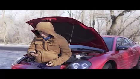 Man-in-winter-coat-stands-near-the-broken-down-car-and-calls-for-help