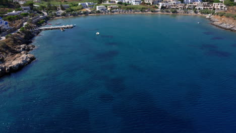 Aerial:-Slow-drone-reveal-shot-of-Megas-Gialos-Beach-in-Syros-island,-Greece-on-a-sunny-day