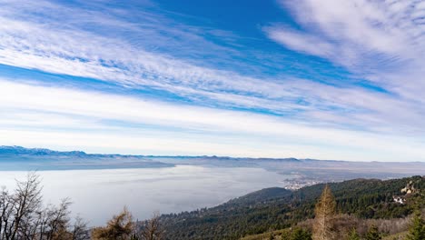 High-angle-shot-over-mountain-range-surrounding-a-lake-in-Bariloche,-Argentina-with-cloud-movement-in-timelapse