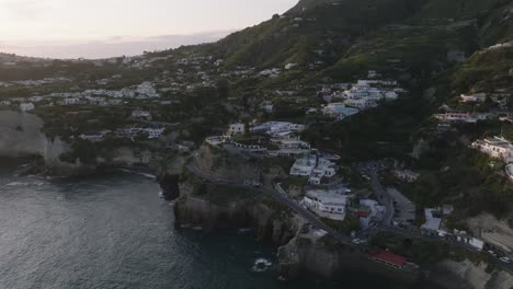 Houses-on-seaside-cliffs-on-Italian-island-of-Ischia,-aerial-pull-out