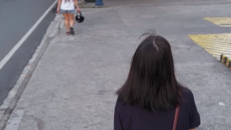 Overhead-following-shot-of-young-Asian-female-uncomfortably-walking-along-city-sidewalk