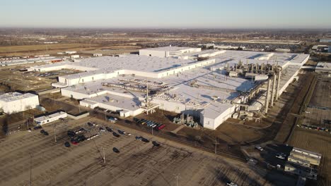 Aerial-forwarding-shot-of-the-huge-ford-mustang-facility-in-Michigan-during-a-sunny-day-with-cars-parked-in-the-parking-lot