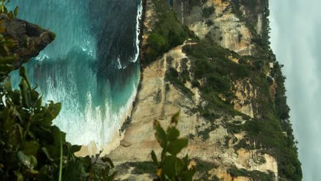 Vertical-Shot-of-the-Cliffs-on-Nusa-Penida-in-Bali,-Indonesia-Overlooking-the-Blue-Sea-with-Waves-on-the-Diamond-Beach-and-Cliffs-on-a-Beautiful-Morning
