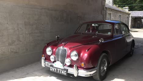 Classic-Jaguar-driving-touch-arch-into-courtyard-on-a-Classic-car-event-in-Waterford-Ireland-early-spring