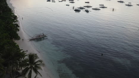 Cinematic-drone-shot-of-the-sunset-in-the-Philppines-with-a-paradisic-beach,-a-tropical-forest-and-boats-in-the-frame,-Asia,-Aerial