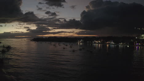 Filmische-Sonnenuntergangsdrohne-über-Dem-Meer-Mit-Booten-Im-Bild-Und-Reflexionen-Entlang-Der-Küste,-Luftaufnahmen,-Philippinen,-Asien