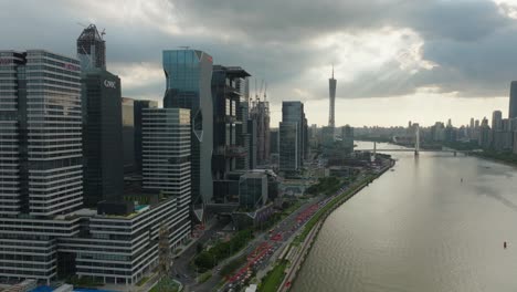 FLy-over-new-development-finance-and-high-tech-complex-by-the-river-coast-in-Guangzhou,-China-on-a-beautiful-cloudy-sunset