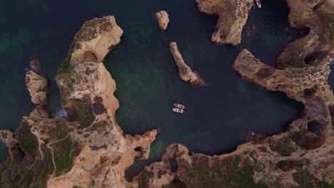 Top-down-aerial-view-of-Ponta-da-Piedade-with-boats-on-water,-Lagos-town,-Algarve-region,-Portugal