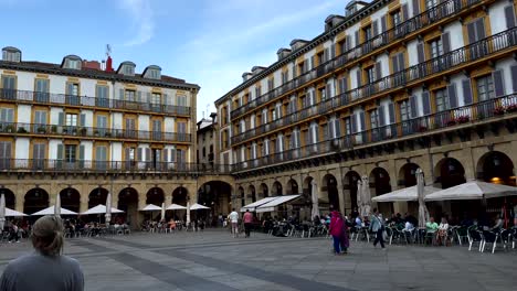 Hermosa-Plaza-Famosa-En-El-Casco-Antiguo-De-San-Sebastián-Con-Arquitectura-Antigua-Y-Gente-Cenando-En-Restaurantes-Al-Aire-Libre---Toma-Panorámica-En-Cámara-Lenta