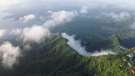 Aerial-cinescape-flying-above-the-clouds-looking-down-on-beautiful-ridgelines,-tropical-rainforests,-ocean,-Philippines