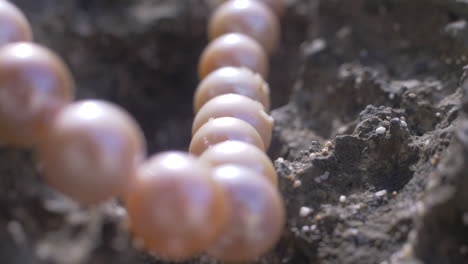 Cinematic-shot-moving-along-a-natural-pearl-necklace-laying-on-natural-rock-on-a-beach,-Slomo,-120-FPS