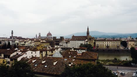 Drone-shot-soaring-over-the-Arno-River-in-Florence,-Italy-with-city-structures-all-around
