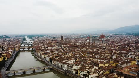 Aerial-view-of-the-River-Arno-cutting-through-Florence,-Italy's-dense-urban-city