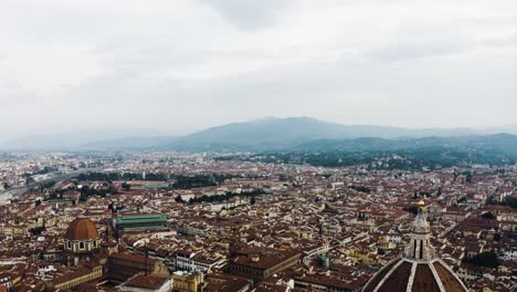 Drone-shot-soaring-far-over-Florence,-Italy-on-a-cloudy-day