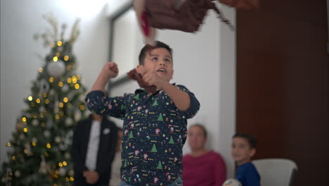 Young-latin-kid-wearing-a-shirt-hitting-fiercely-a-brown-reindeer-pi√±ata-with-his-fist