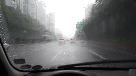 Driver-drives-the-car-in-heavy-rain-on-Gangnam-highway-in-Seoul-city,-view-through-the-windshield-of-the-car