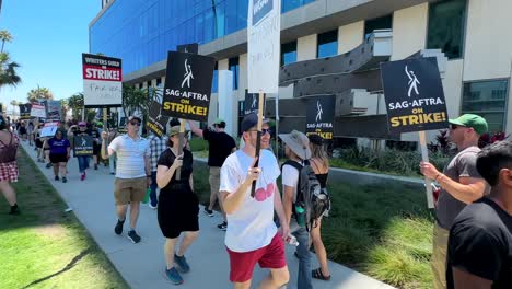 Screen-Actors-SAG-AFTRA-and-Writers-Guild-of-America-Unions-on-Strike-in-Hollywood,-People-Walking-With-Signs-in-Front-of-Netflix-Office-Building