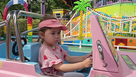 Porträt-Eines-Kaukasischen-Kleinen-Mädchens,-Das-Das-Lenkrad-Eines-Spielzeugautos-Im-Vergnügungspark-Seoul-Land-Dreht