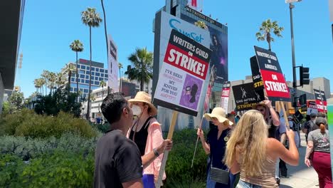 Hollywood-Strike-in-Front-of-Netflix-Building,-SAG-AFTRA-and-Writers-Guild-of-America-Signs-in-Hands-of-Protesters-Walking-on-Sidewalk