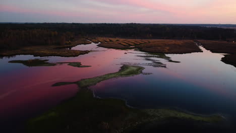 Red-vivid-sky-reflecting-on-calm-lake-water,-aerial-drone-view