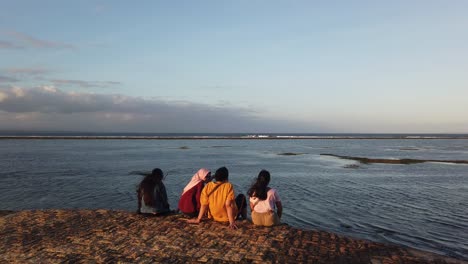 Indonesian-Girls,-Friends-Relax-at-Beach-Shore-Dock,-Seascape-of-Sanur-Bali-Blue-Landsacpe,-Sea-at-Low-Tide