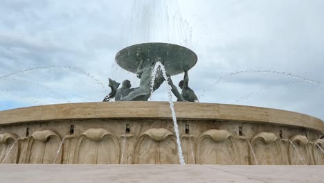 Ancient-Triton-Fountain-in-front-of-the-Valletta-Fortress-in-Malta-with-cloudy-blue-sky