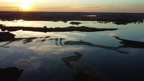 Cinematic-sunset-reflecting-on-water-of-swamp,-aerial-drone-view