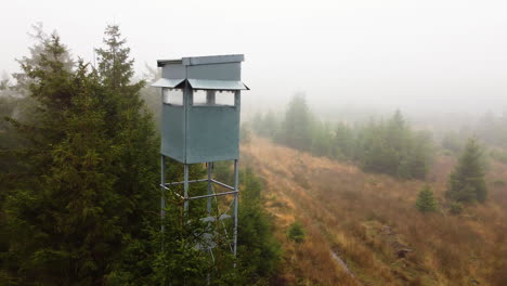 A-drone-pans-to-a-watch-tower-in-a-forest-filled-with-mist-in-Belgium