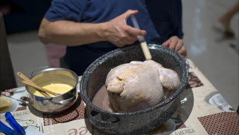 Close-up-of-the-hands-of-an-hispanic-mature-man-injecting-a-concoction-of-his-own-to-a-raw-turkey-preparing-for-christmas-thanksgiving