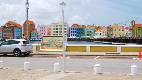 4k-60fps-cinematic-parallax-fly-by-pan-of-iconic-colorful-world-heritage-UNESCO-buildings-and-the-floating-Queen-Emma-Bridge-in-the-city-of-Willemstad,-Curacao