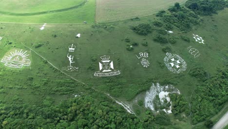 Umlaufende-Luftaufnahme-über-Fovant-Militärabzeichen,-Die-In-Das-Wahrzeichen-Der-Kreidehügel-Ackerlandschaft-Von-Wiltshire-Eingraviert-Sind