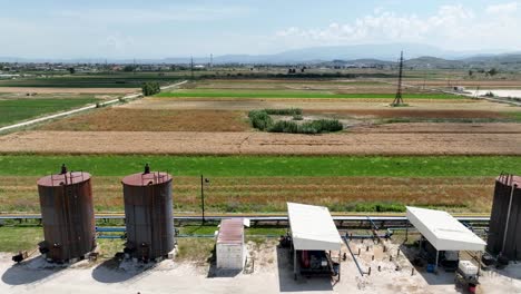 Panoramic-shot-of-industrial-oil-tanks-next-to-farming-fields-causing-pollution