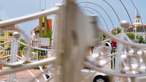 4k-60fps-Filmischer-Parallaxenflug-Im-Schwenk-Der-Schwimmenden-Königin-Emma-Brücke-Mit-Touristen-Und-Fußgängern,-Die-Darüber-Laufen,-Und-Vorbeifahrenden-Autos,-In-Der-Stadt-Willemstad,-Curaçao
