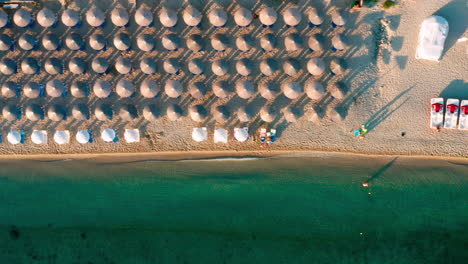 Vista-De-Arriba-Hacia-Abajo-De-La-Playa-Con-Sombrillas-En-Hanioti,-Grecia