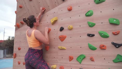 Woman-ascending-a-bouldering-wall-outdoors,-cinematic-shot