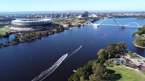 Drone-Aerial-View-descending-down-over-Optus-Stadium-and-Matagarup-Bridge-with-boats-leaving-wakes-on-the-Swan-River-in-Perth,-Western-Australia