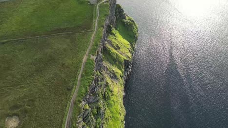 Drone-shot-of-the-Cliffs-of-Moher-at-sunset,-top-down-over-the-cliffs-and-waves