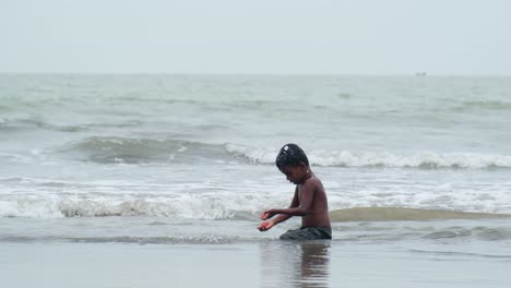 Schwarzes-Kind-Spritzt-Wasser-In-Seinen-Körper,-Um-Die-Sommerhitze-Am-Meeresstrand-In-Cox&#39;s-Bazar,-Bangladesch,-Zu-Genießen
