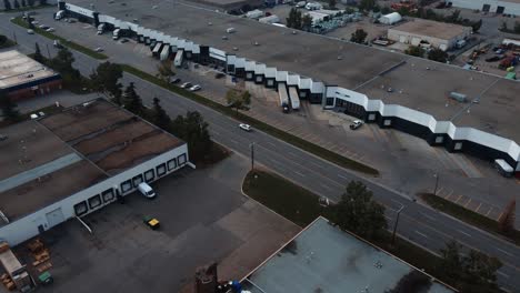 Revealing-drone-shot-of-the-bays-at-the-warehouse-with-parked-semi-trucks-in-Calgary,-Alberta