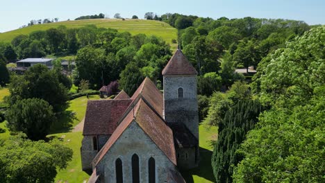 A-push-in-shot-of-St-Lawrence-the-Martyr-church-in-Godmersham,-with-surrounding-bright-green-fields-and-trees