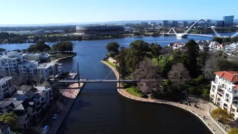 Drone-Aerial-View-descending-down-over-East-Perth-then-180-degree-rotation-to-Optus-Stadium,-Matagarup-Bridge-and-suspension-bridge-in-Claisebrook-Cove-in-Perth,-Western-Australia