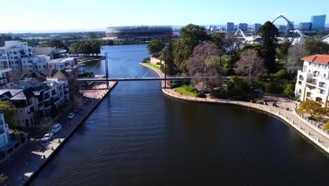 Drone-Aerial-View-descending-down-over-water-into-Claisebrook-Cove,-East-Perth-over-Optus-Stadium-and-Matagarup-Bridge-in-Perth,-Western-Australia
