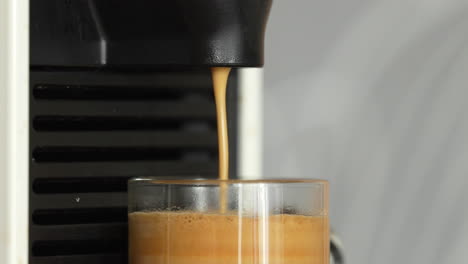Kaffee-In-Einer-Schönen-Transparenten-Tasse-Mit-Einer-Automatischen-Espressomaschine-Zubereiten-–-Nahaufnahme-Vom-Rand-Der-Tasse-Und-Einem-Teil-Der-Espressomaschine