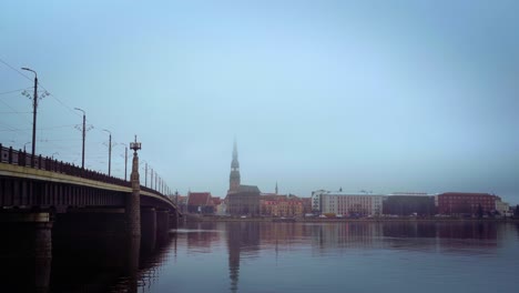 Riga,-capital-of-Latvia-seen-from-Daugava-river-with-fog-and-Akmins-Tilts-bridge-total-fixed-shot