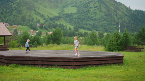 Little-girl-runs-along-wooden-ground-with-younger-brother