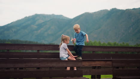 Little-boy-presents-small-bouquet-to-elder-sister-on-benches