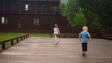 Little-boy-chases-sister-running-along-wooden-dance-deck