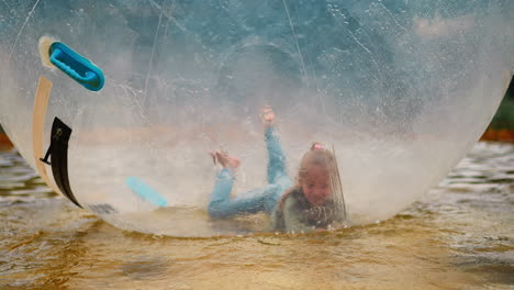 Funny-girl-jumps-and-falls-inside-large-water-globe-in-pool