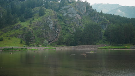 Landscape-with-rocky-hill-and-wild-forest-on-bank-of-lake